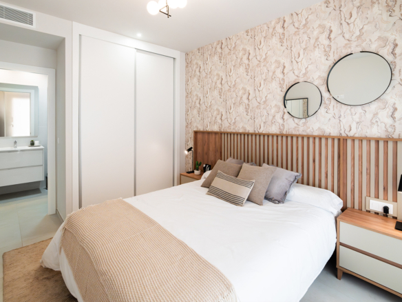 Hoofdslaapkamer met tweepersoonsbed en grote ramen in kustappartement