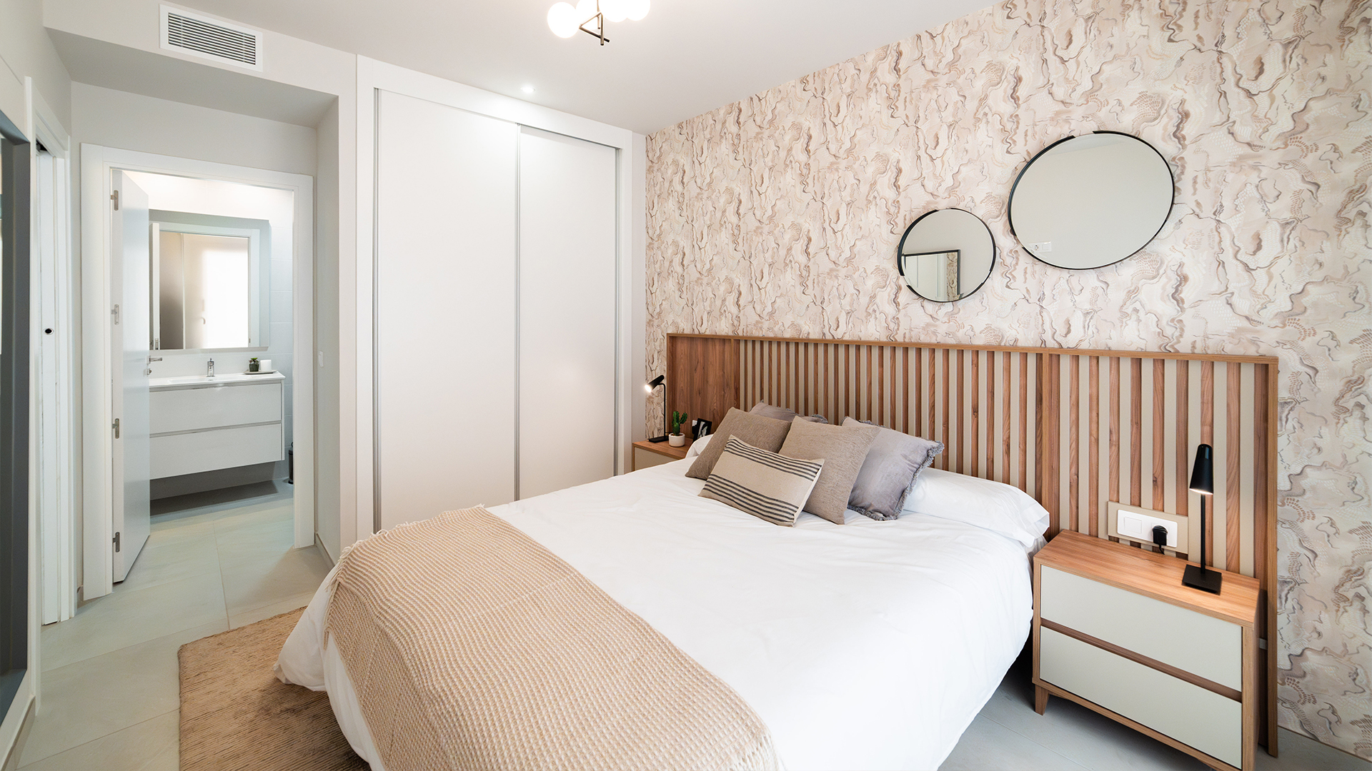 Hoofdslaapkamer met tweepersoonsbed en grote ramen in kustappartement