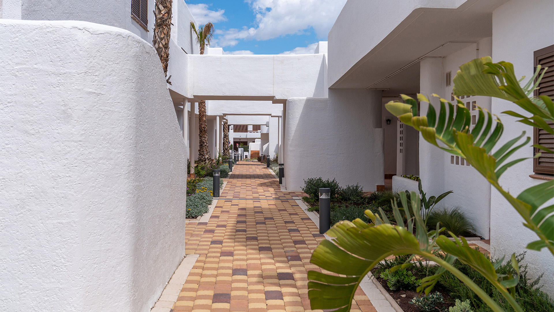 Entree van het woonresort met mediterrane beplanting en voetpaden