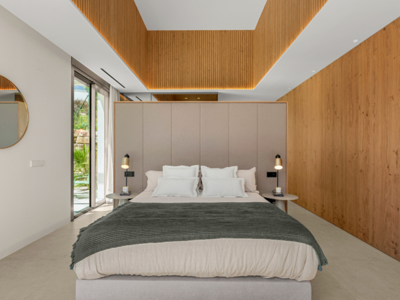 Modern hotel bedroom with a beige upholstered headboard, white bedding, gray throw, and warm wood paneling along the walls.] , but (this is wrong)