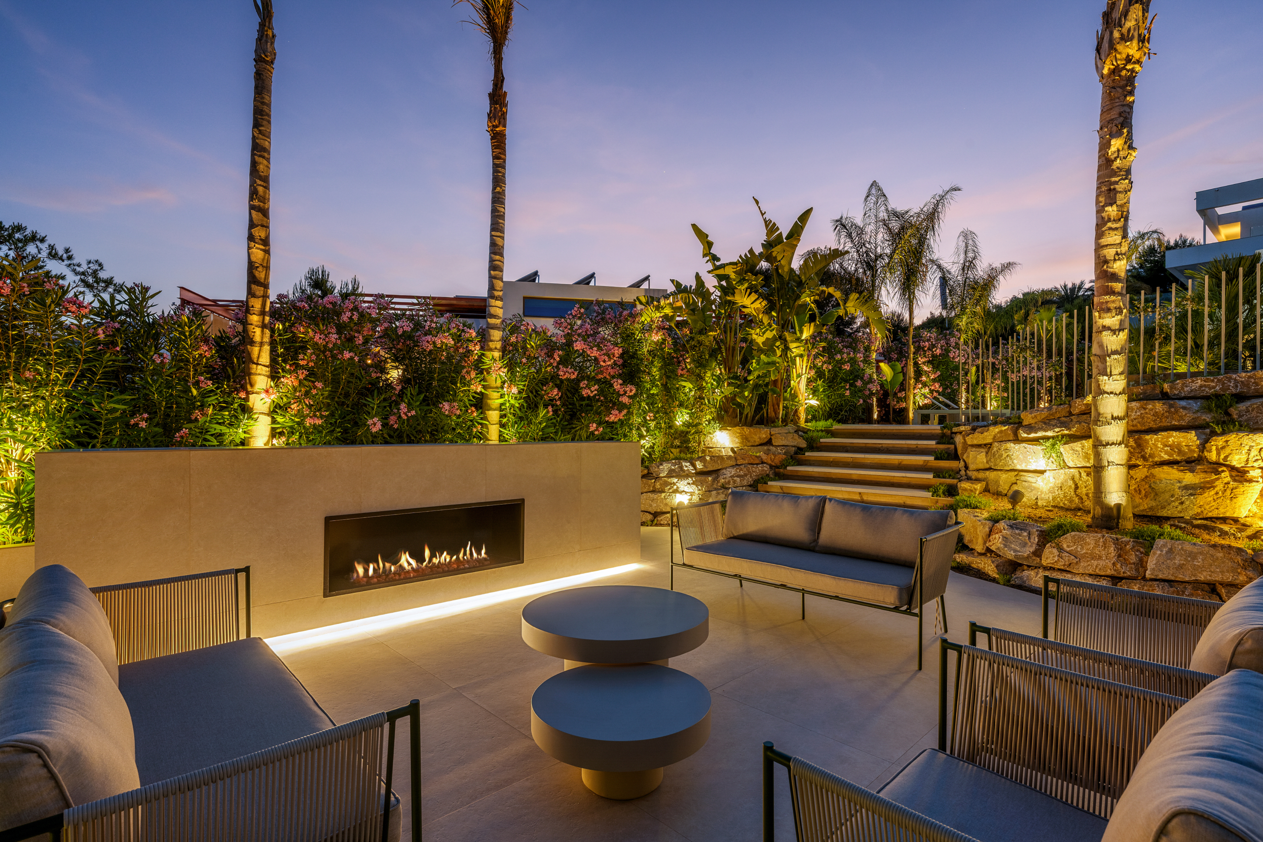 Luxe villa Las Colinas met sfeervolle buitenlounge, haard en verlichte tuin bij zonsondergang