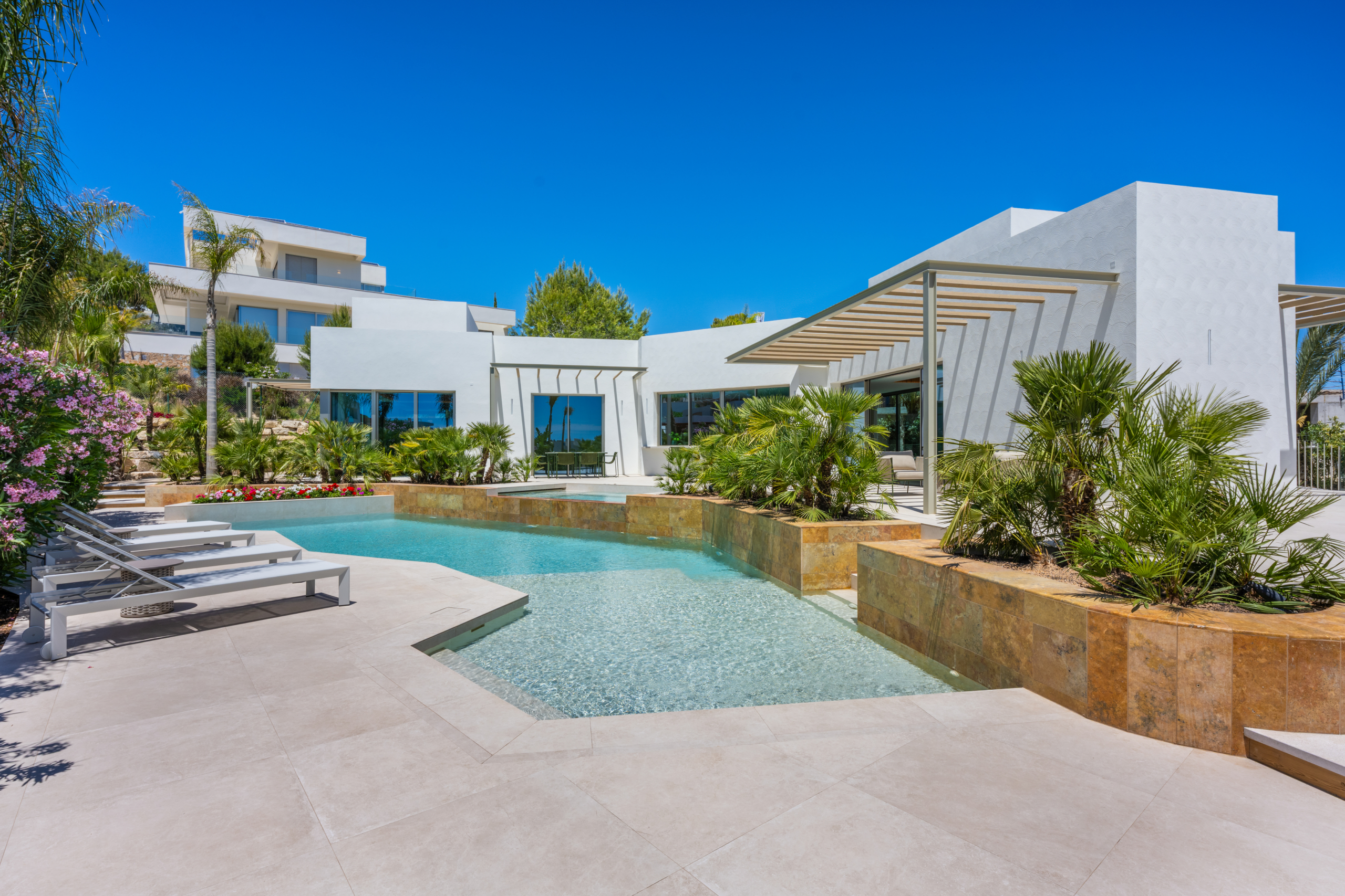 Luxe villa Las Colinas met modern wit exterieur, privézwembad en tropische beplanting.