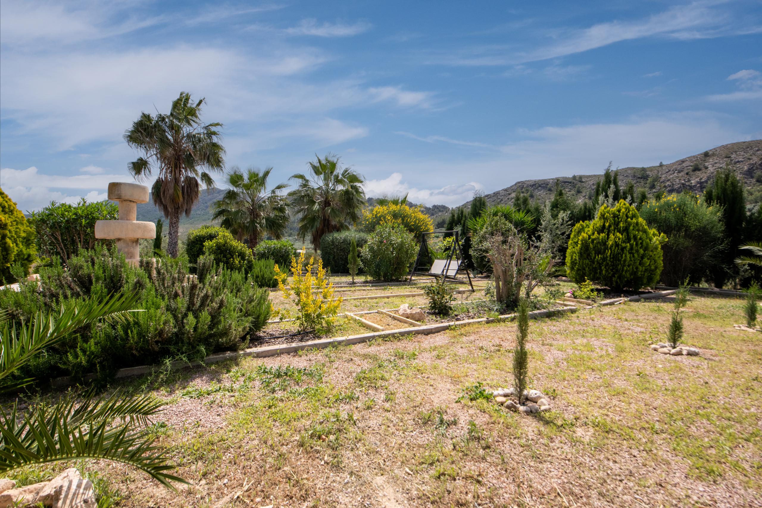 Aangelegde voortuin met volwassen bomen, fontein en mediterrane beplanting bij villa in Calasparra