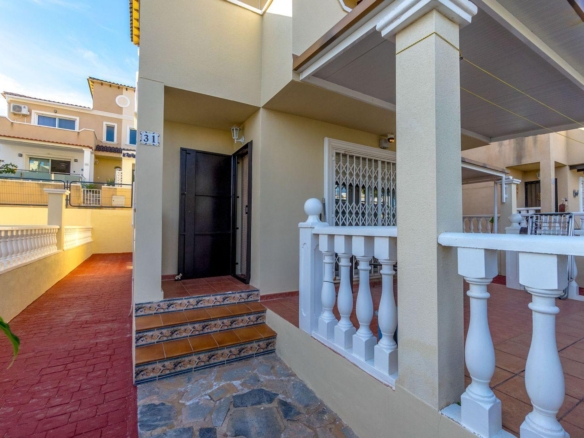 Front entrance of a beige two-story home with white balustrade, tiled steps, and a black front door