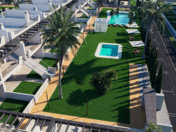 Aerial view of a resort with white townhouses, palm trees, and two turquoise pools on green lawns.