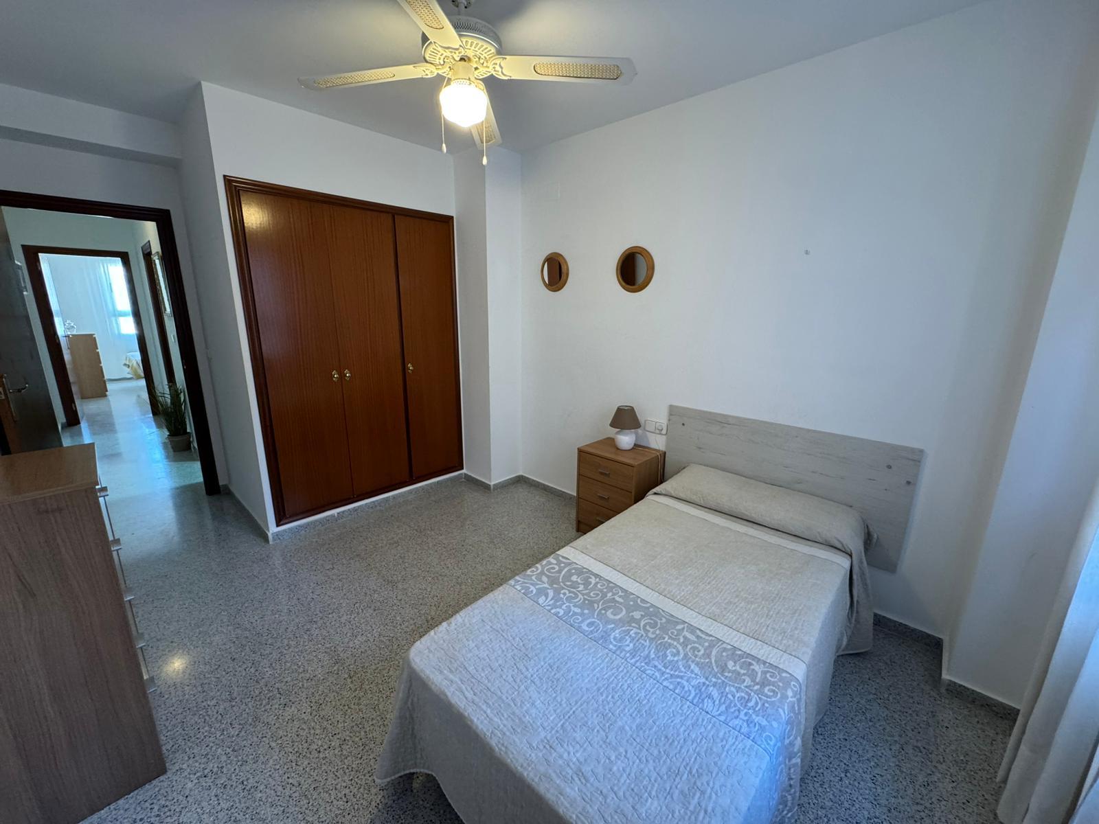 Small bedroom with a single bed, nightstand, and two round wall mirrors above the bed