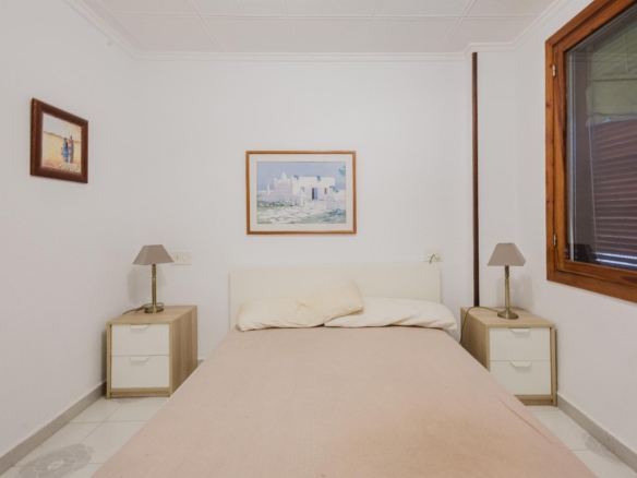 Bedroom with a centered bed, two matching nightstands, and framed art on the walls.