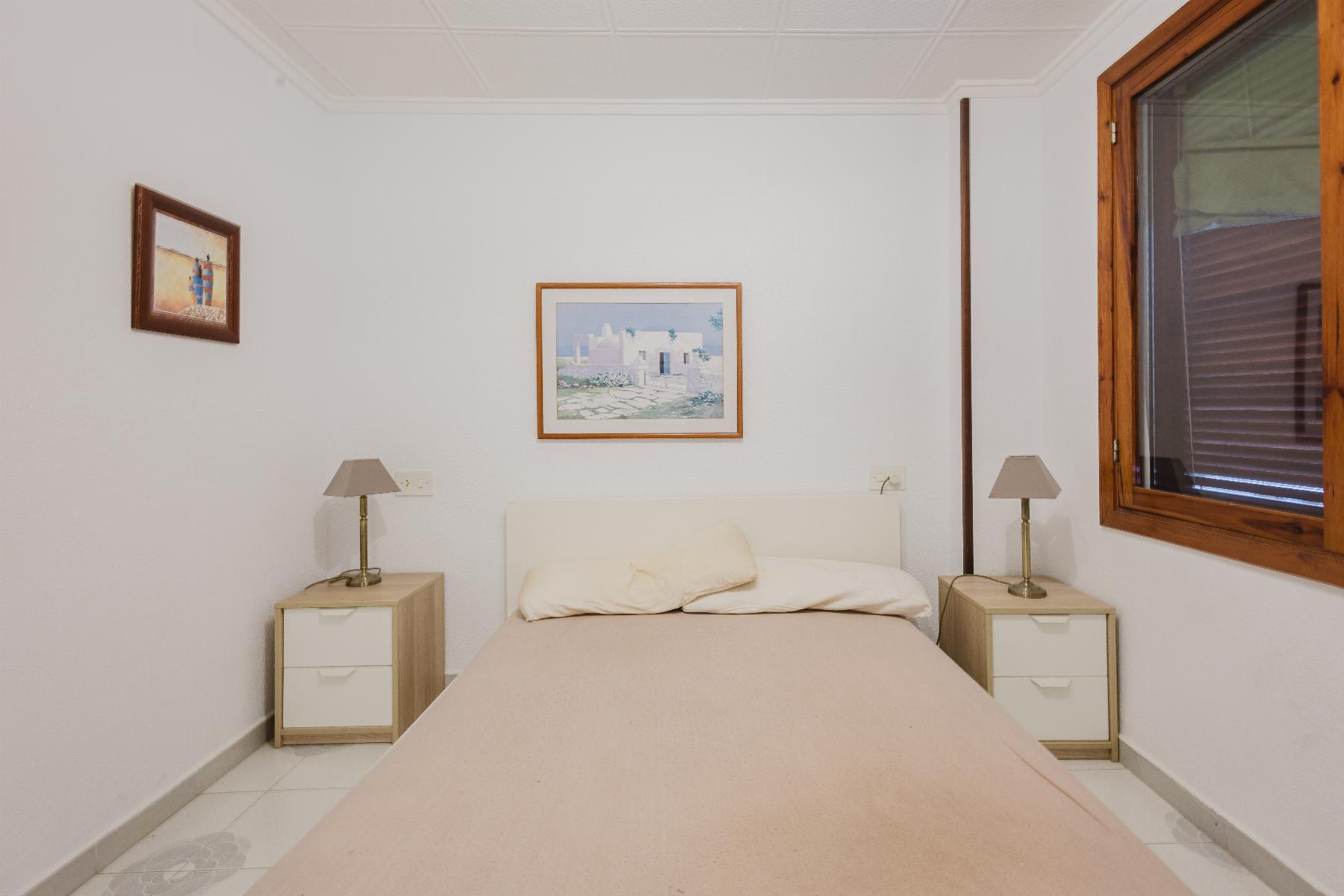 Bedroom with a centered bed, two matching nightstands, and framed art on the walls.