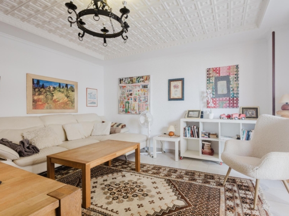 Cozy living room with a beige sectional sofa, wooden coffee tables, and a patterned rug under wall art.