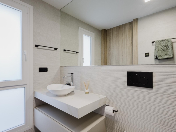 Contemporary bathroom with frosted windows, wall-mounted storage cabinets, and a large mirror reflecting a wooden panel accent.