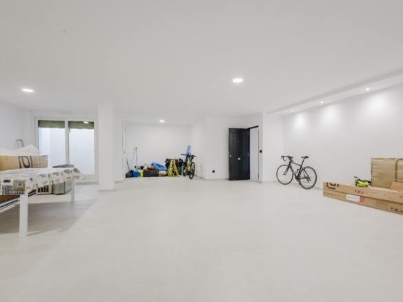 Bright white basement/garage storage area with a bicycle against the wall, boxes, and packing gear along the left side.