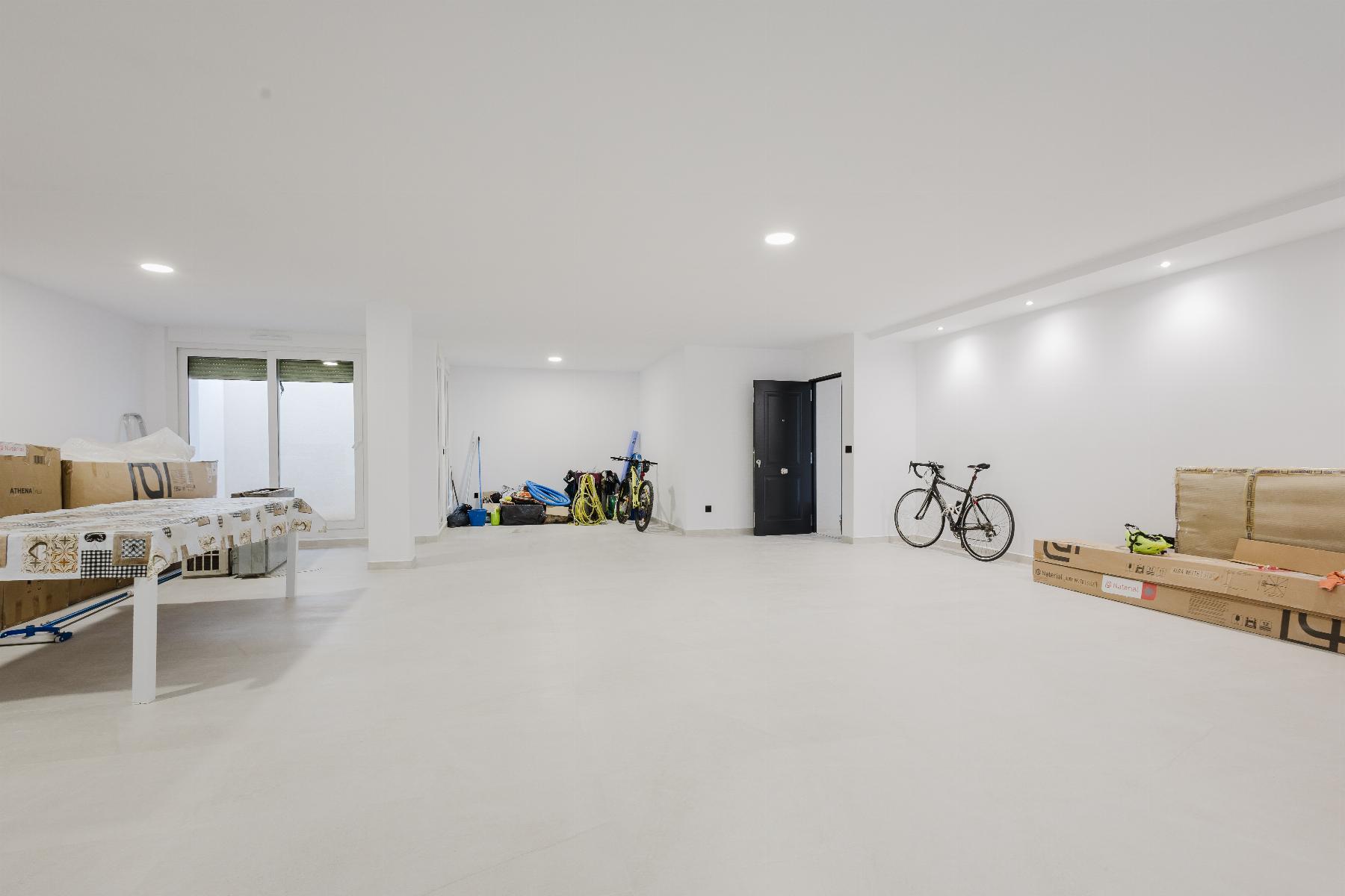 Bright white basement/garage storage area with a bicycle against the wall, boxes, and packing gear along the left side.