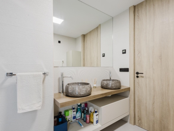 Modern bathroom with two round stone vessel sinks on a wooden countertop and a large mirror above the sinks.