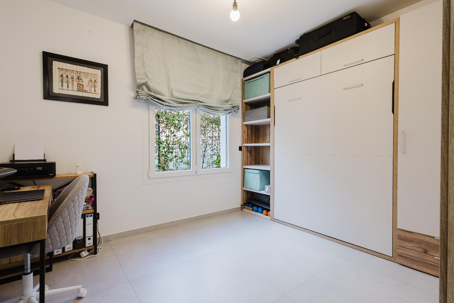 Home office corner with a desk and printer on the left, and a tall white wardrobe with shelves on the right.