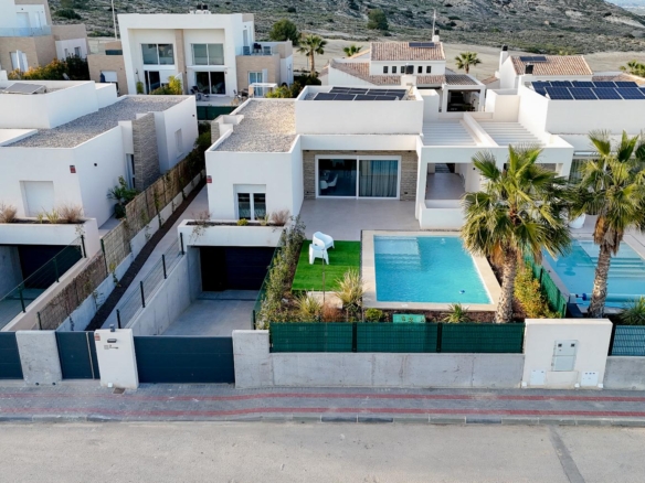 Aerial view of a modern hillside residential complex with white boxy homes and blue swimming pools.0 pensaike