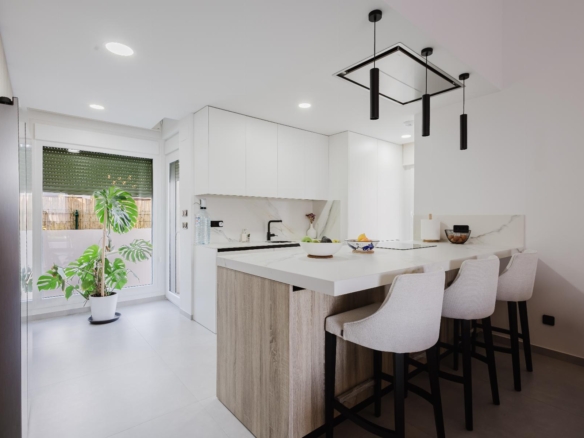 Bright modern kitchen with white cabinets, marble backsplash, and a wooden island island bar with beige stools.