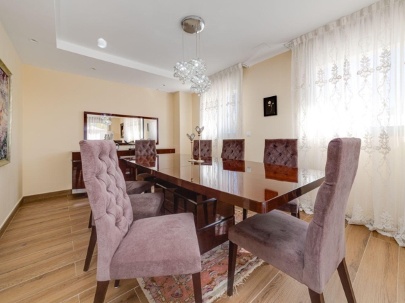 Elegant dining room with a glossy wooden table, tufted lavender chairs, and a crystal chandelier.