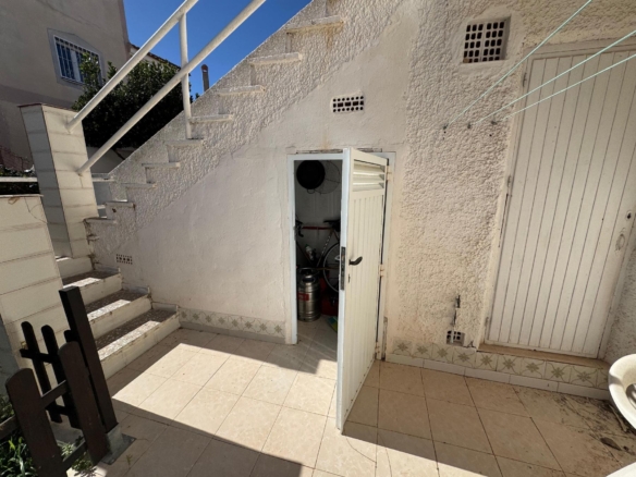 Outdoor stairwell and courtyard with a small open storage closet containing gas cylinders inside at the bottom of the stairs.