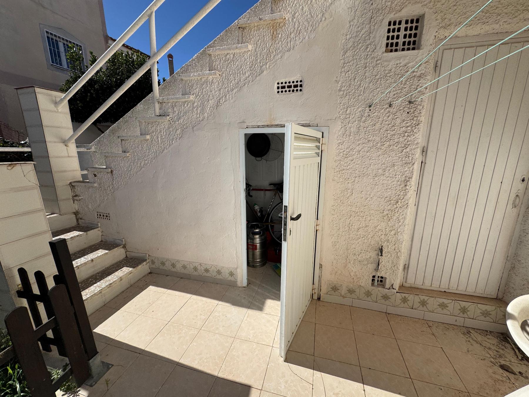 Outdoor stairwell and courtyard with a small open storage closet containing gas cylinders inside at the bottom of the stairs.