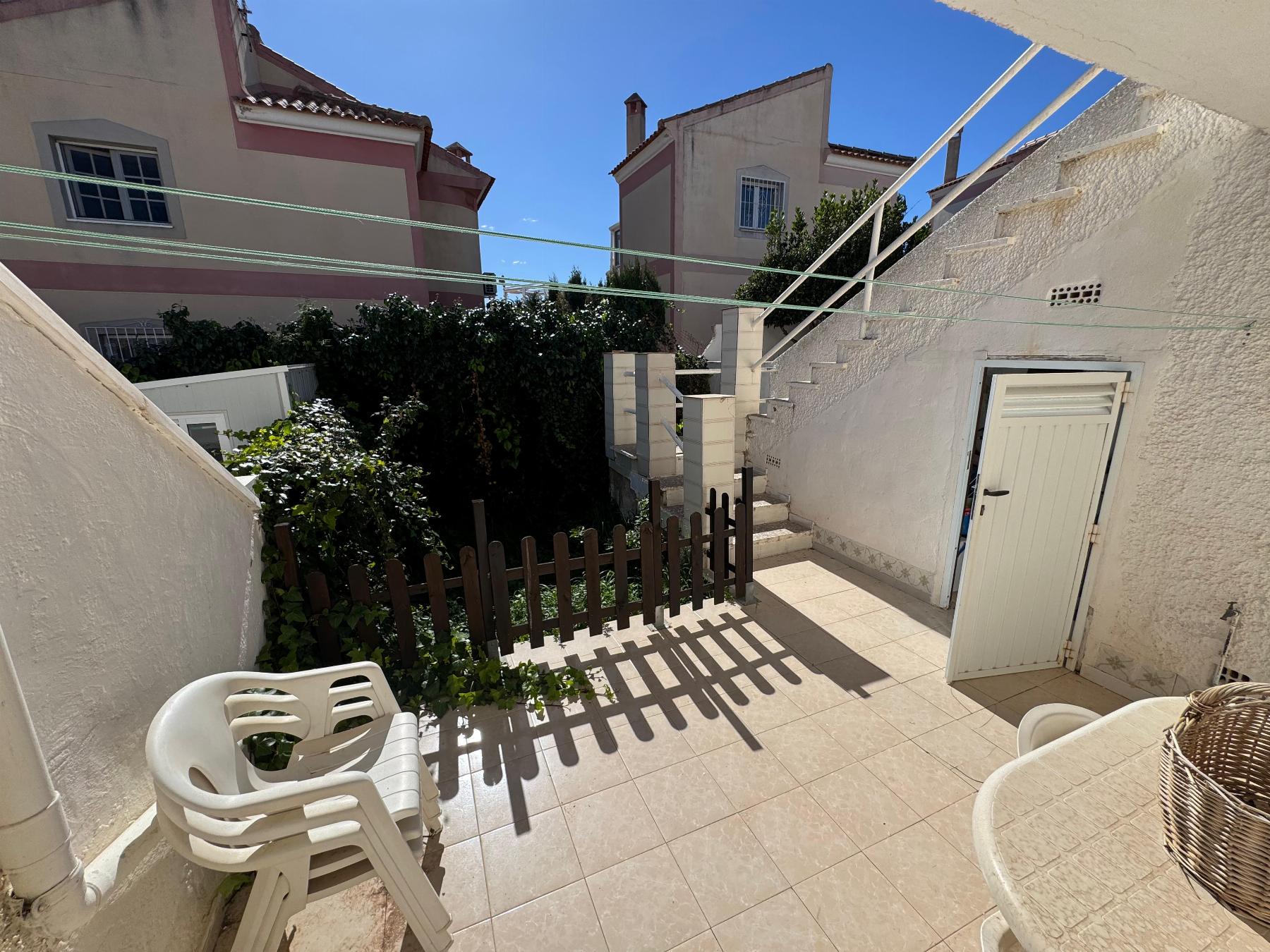 Sunny sunny courtyard with white walls and pastel buildings, tiled patio, and overhead clotheslines across the space.