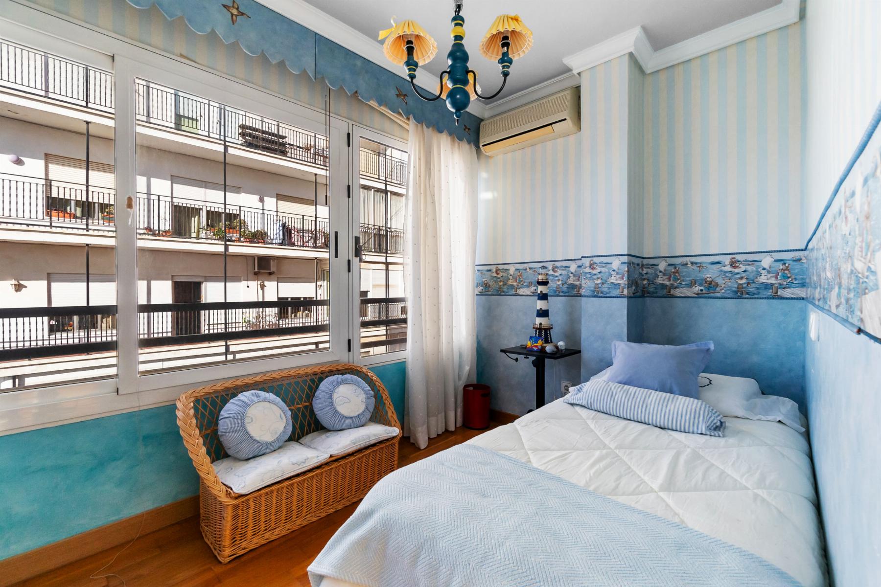 Bright nautical‑themed bedroom with blue stripes, twin beds, a wicker bench, and large windows opening to a balcony.