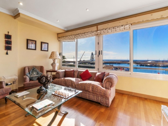 Bright living room with peach sofas, a glass coffee table, and a marina view through wide windows.
