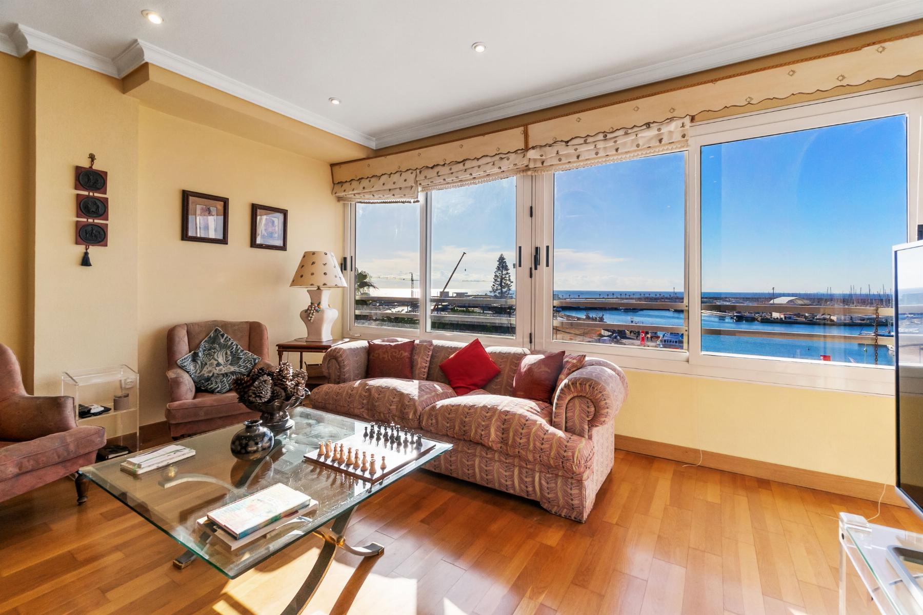 Bright living room with peach sofas, a glass coffee table, and a marina view through wide windows.
