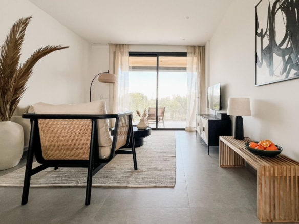 Bright modern living room with woven chairs facing a sliding glass door to a balcony and a rug-lined floor.