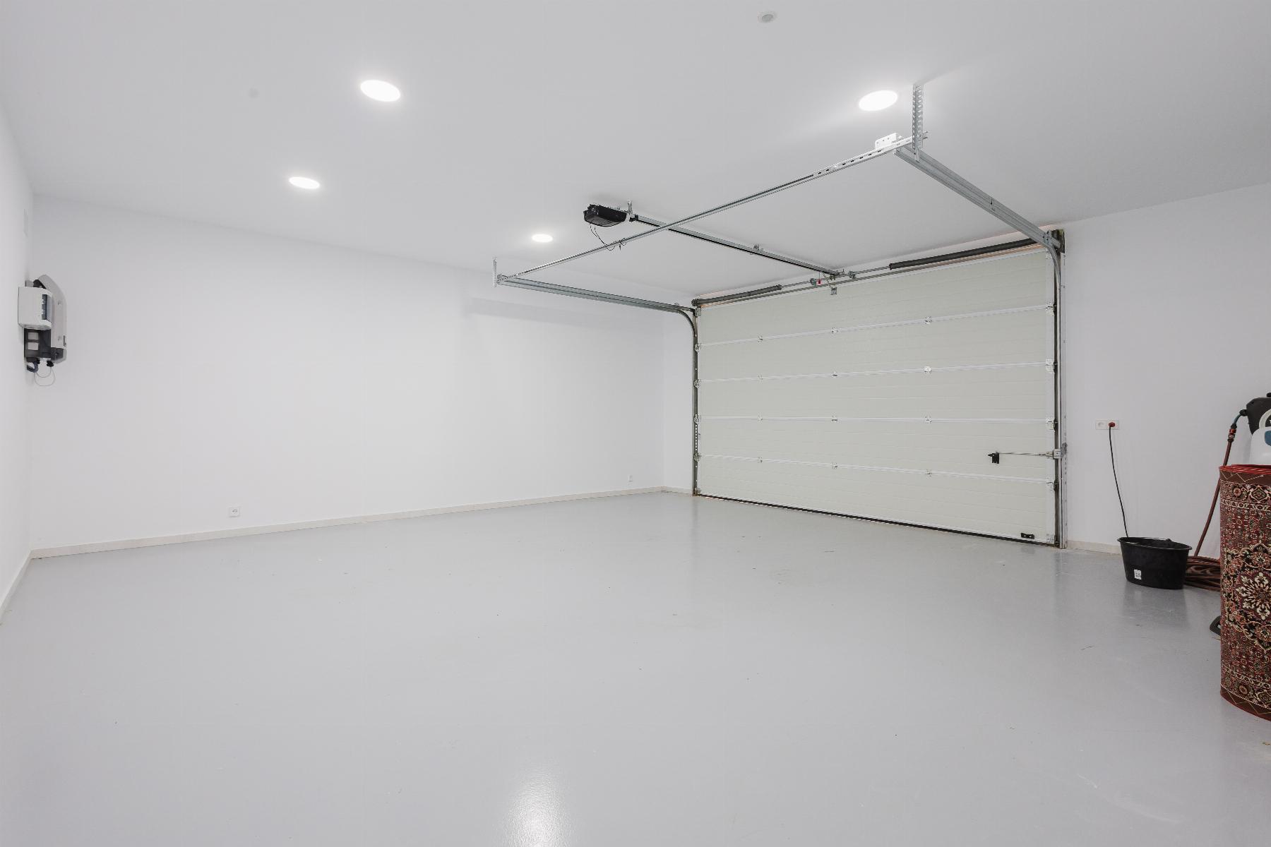 Empty home garage with a white interior, closed sectional door, and bright recessed ceiling lights.