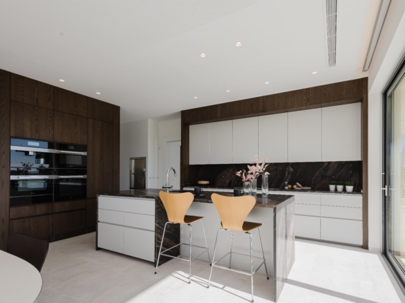 Modern kitchen with dark wood cabinetry, white upper cabinets, and a marble island with two wooden bar stools.