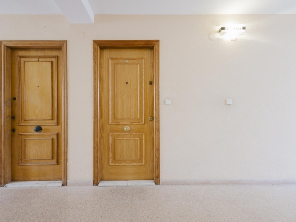 Two wooden apartment doors labeled 2 and 3 in a beige hallway with a wall light on the right side