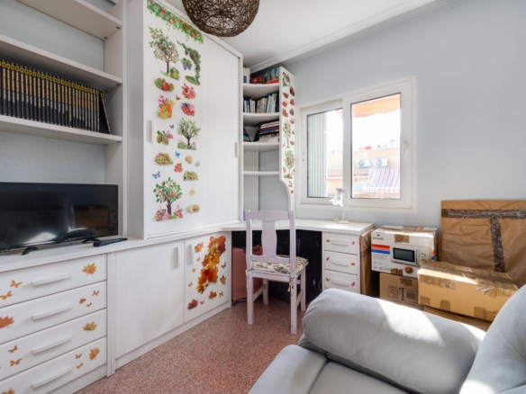 White built-in desk and cabinets decorated with autumn leaf stickers, a chair, bookshelves, a small TV, and a window in a bright room.
