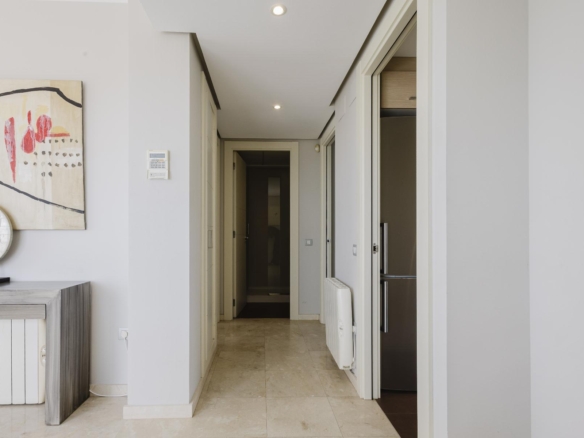 Bright, modern hallway with light gray walls, abstract painting on the left, and doors at the far end.