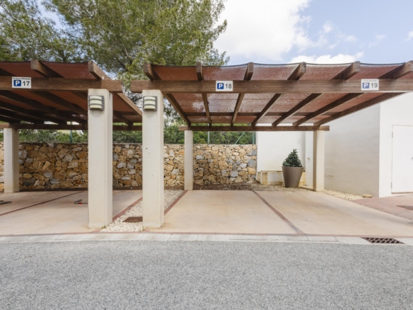 A covered parking area with wooden beams, concrete columns, and a stone wall in the background, labeled spots P17–P19 with a potted plant near a white wall and door on the right