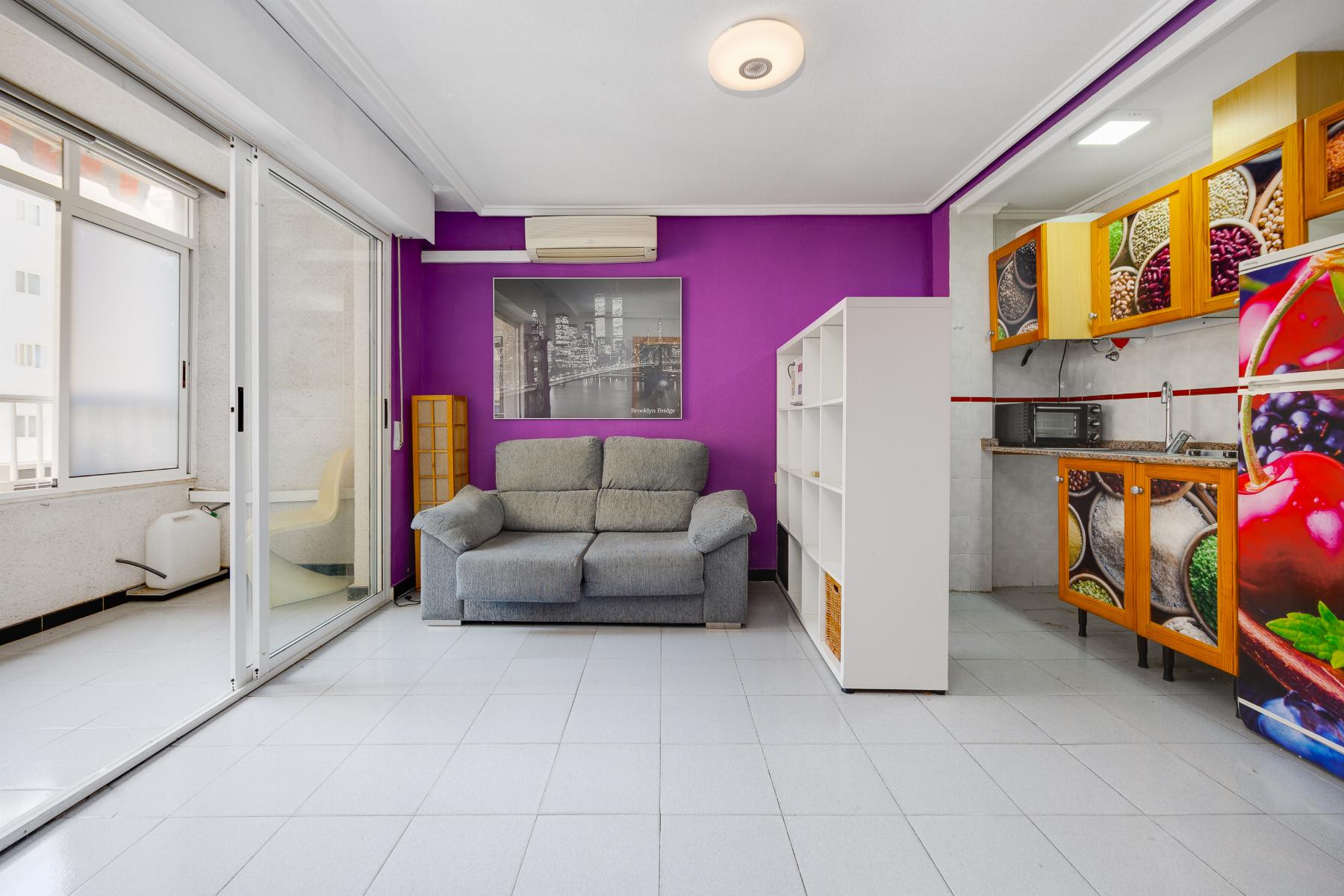 Purple-walled living area with a gray sofa, white cubby shelves, and a black-and-white city print above the sofa.
