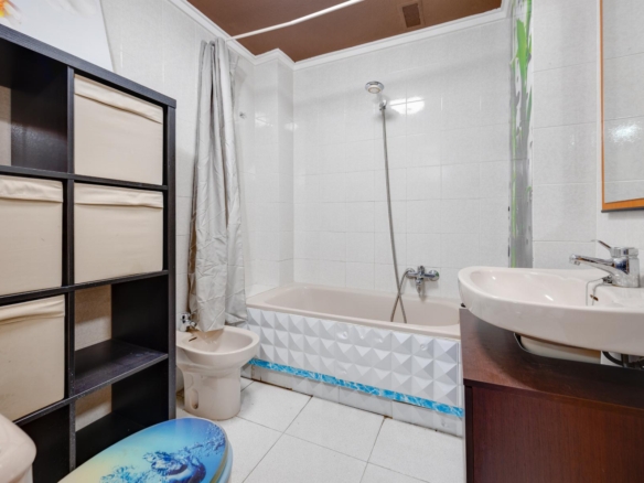 Bathroom with a white bathtub, wall tiles, and a chrome handheld shower above the tub.