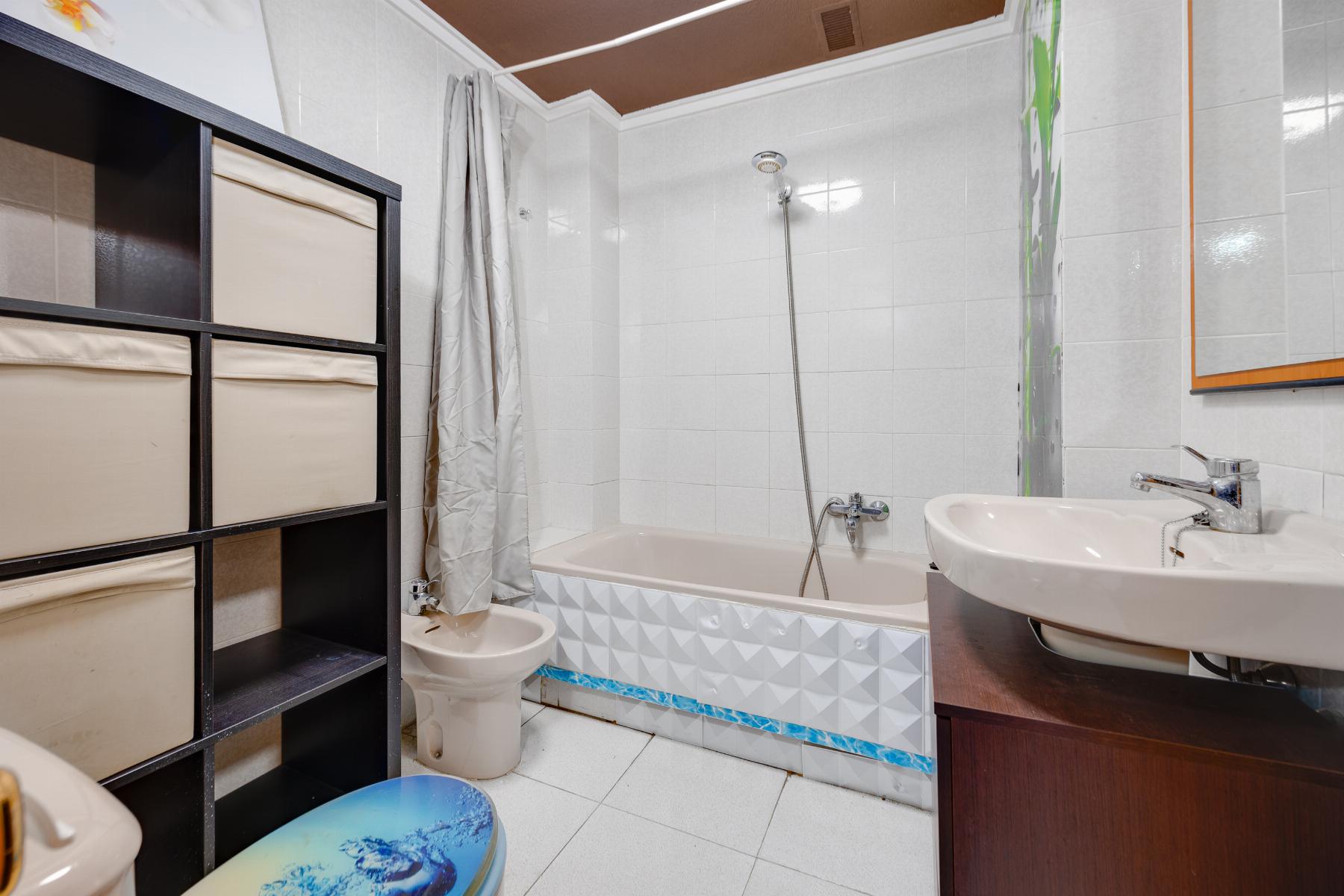 Bathroom with a white bathtub, wall tiles, and a chrome handheld shower above the tub.