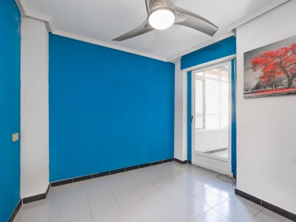 Blue-walled room with white trim, a white ceiling fan, and a glass door to the outside; a red-tree landscape painting hangs on the wall to the right.