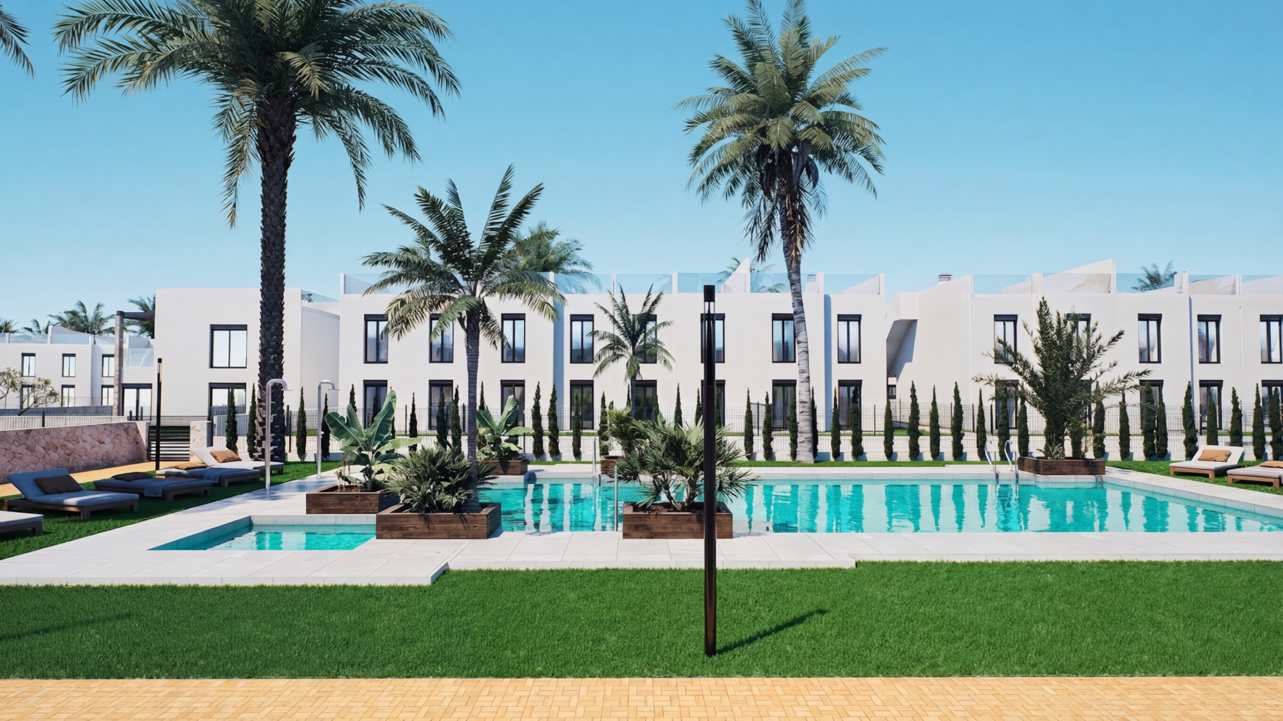 Modern resort courtyard with a rectangular turquoise pool, white buildings, and tall palm trees under a clear blue sky. Six lounge chairs line the pool deck.