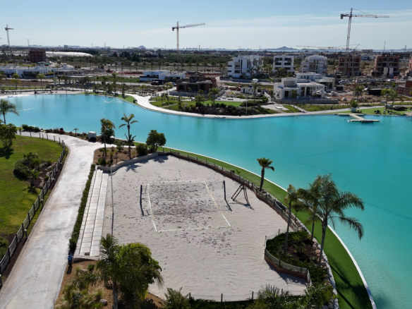 Dronebeeld van Santa Rosalía met centraal meer, strandzone, beachvolleyveld en palmbomen.