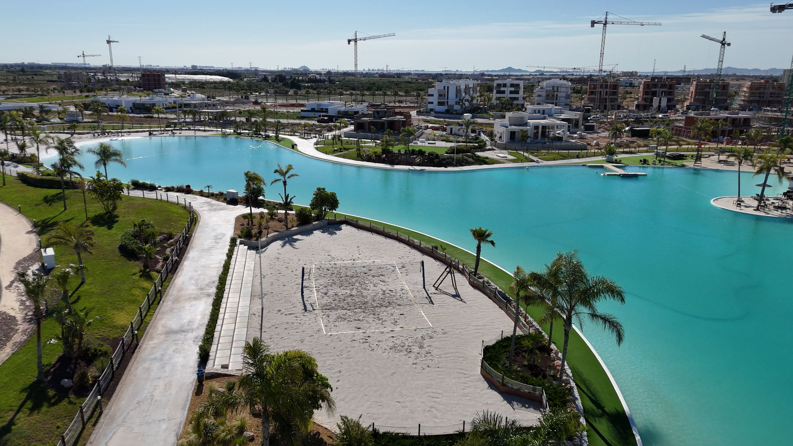 Dronebeeld van Santa Rosalía met centraal meer, strandzone, beachvolleyveld en palmbomen.