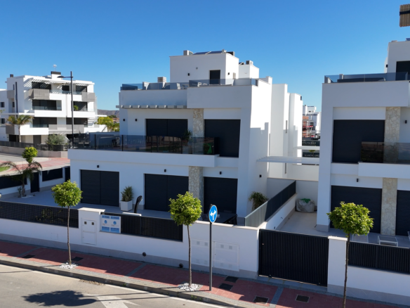 Modern white apartment buildings with black shutters and glass balconies along a sunny street.
