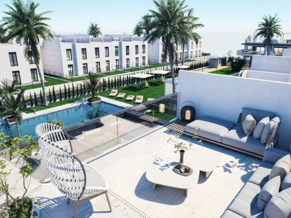 Modern white resort courtyard with a rectangular pool, palm trees, and lawned seating areas on a sunny day.