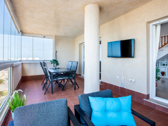 Groot balkon van penthouse in Puerto Mar 3 met zitgedeelte, eettafel en glazen afsluiting
