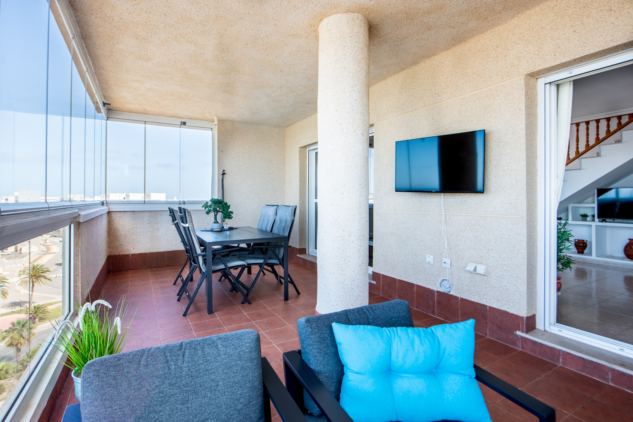Groot balkon van penthouse in Puerto Mar 3 met zitgedeelte, eettafel en glazen afsluiting