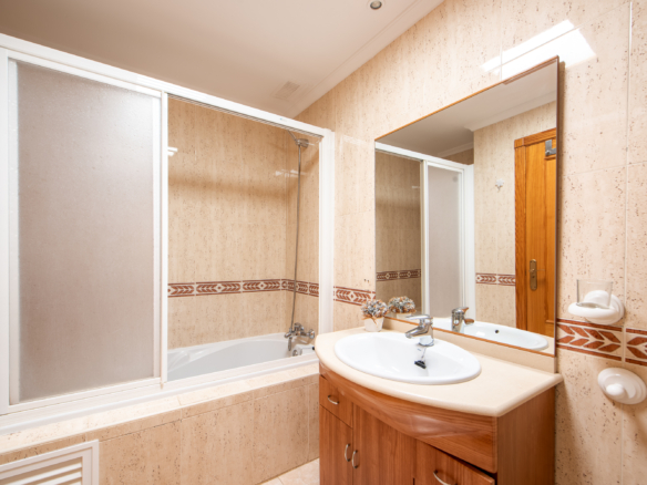 Badkamer met ligbad, wastafel en houten badkamermeubel in appartement La Manga