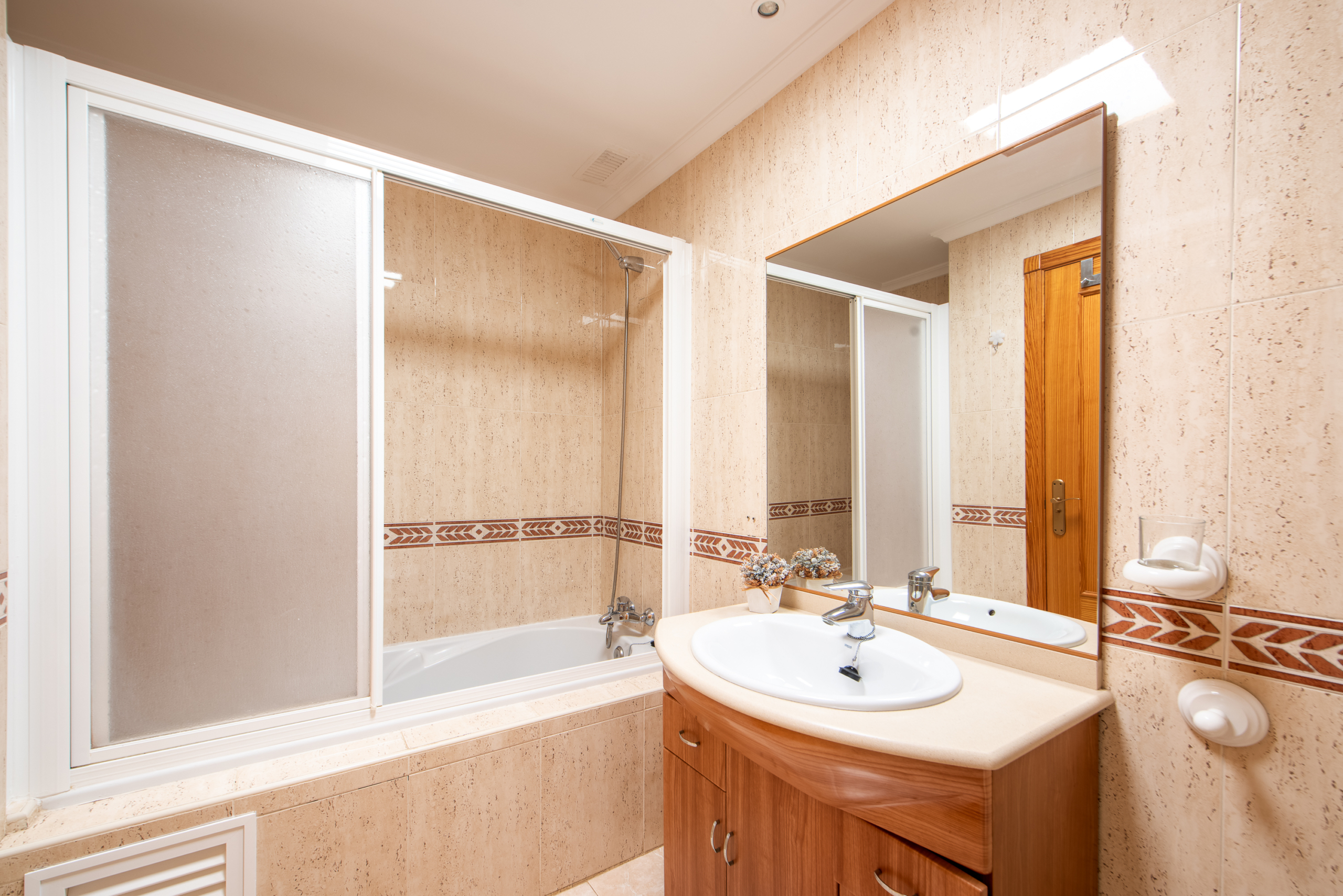 Badkamer met ligbad, wastafel en houten badkamermeubel in appartement La Manga
