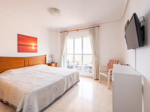 Hoofdslaapkamer met tweepersoonsbed, balkon en veel licht in penthouse Puerto Mar 3