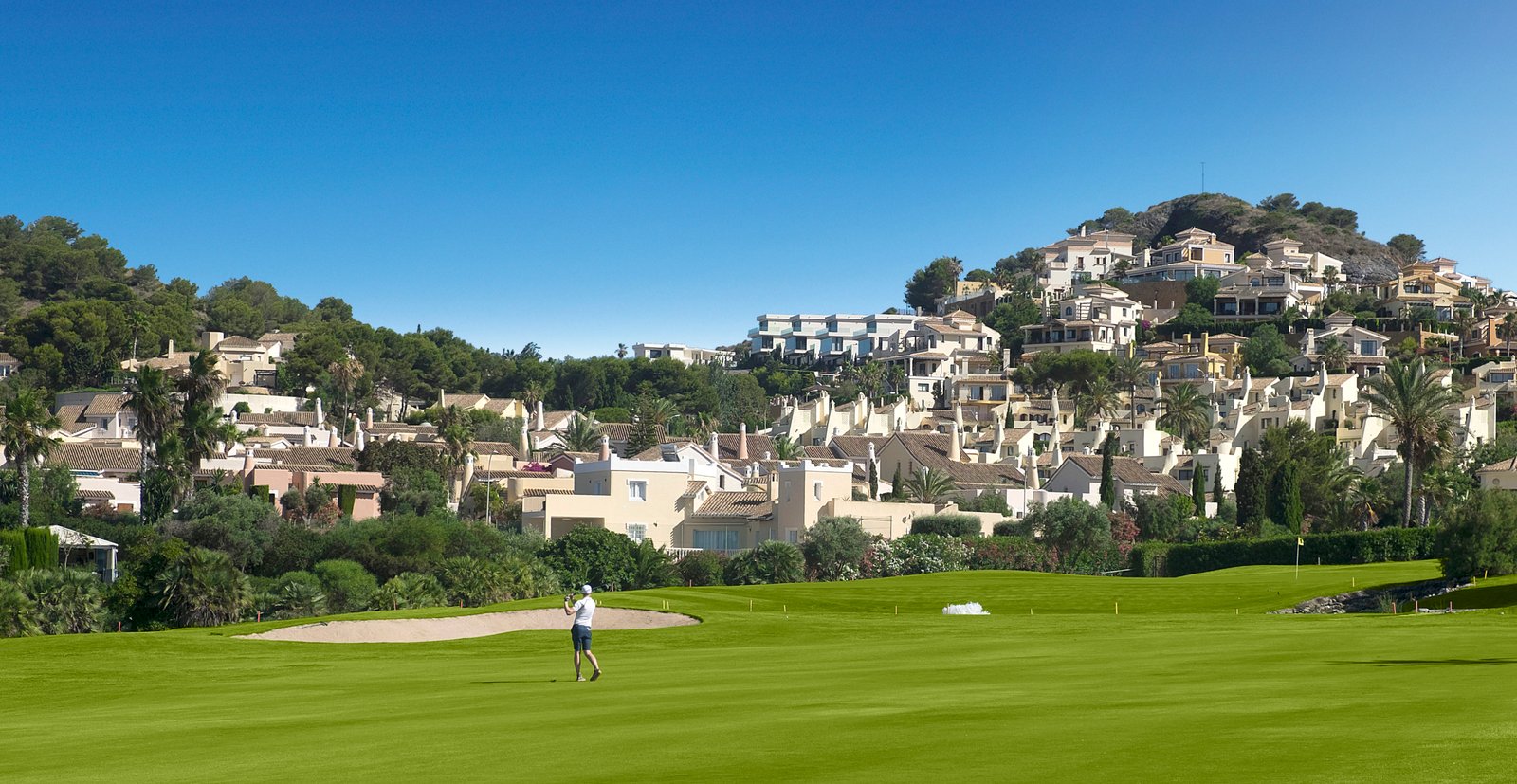 Golfbaan met groene fairway en woningen tegen de heuvels, nabij nieuwbouw in La Manga Club