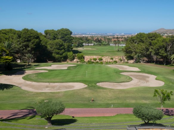 Golfgreen omringd door zandbunkers en bomen, nabij nieuwbouw in La Manga Club